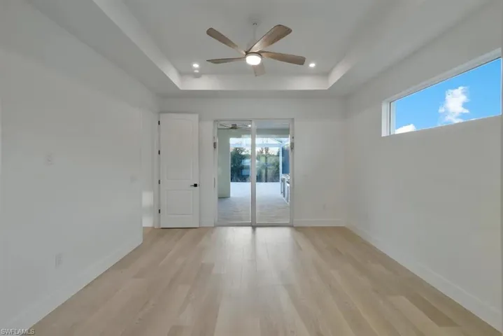 Unfurnished room featuring a ceiling fan, light wood finished floors, a tray ceiling, and recessed lighting