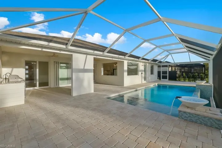 Swimming pool with a sunroom, a lanai, a patio, and exterior kitchen