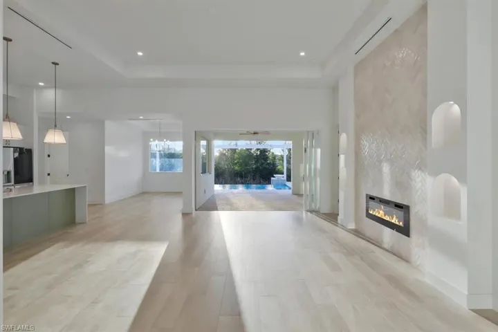 Unfurnished living room with a fireplace, light wood-style flooring, a tray ceiling, and recessed lighting