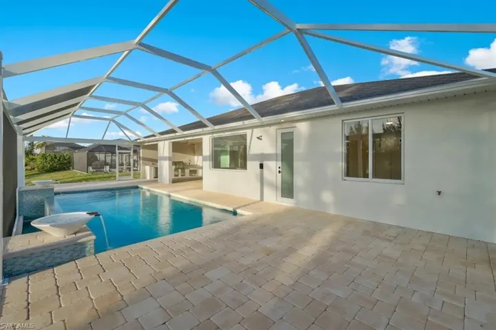 Outdoor pool featuring a sunroom, a patio area, and glass enclosure