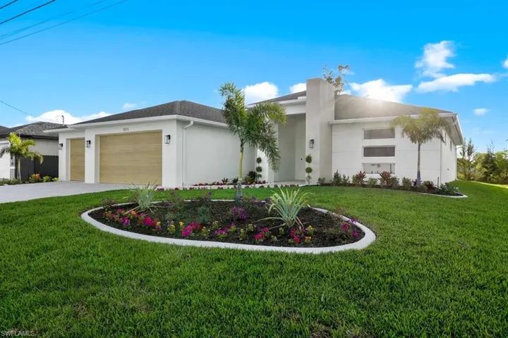 View of front facade with an attached garage, stucco siding, a front lawn, and driveway
