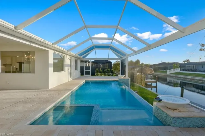 Integrated pool / hot tub with a sunroom, a lanai, a patio, and a water view