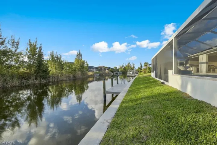 Dock area with a lawn, a lanai, a water view, and a sunroom