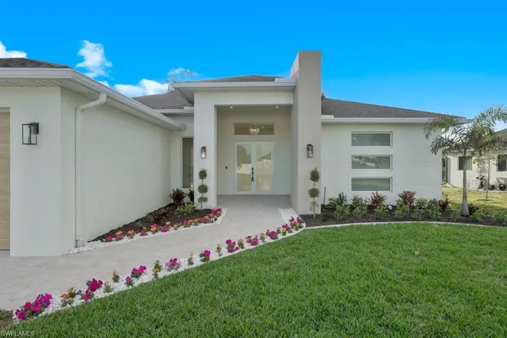 Property entrance featuring stucco siding, roof with shingles, french doors, and a lawn