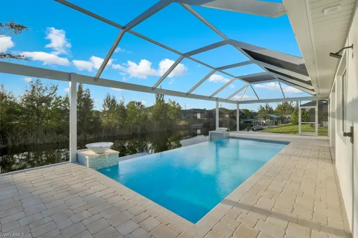 View of pool with a sunroom, patio surround, an infinity pool, and a lanai
