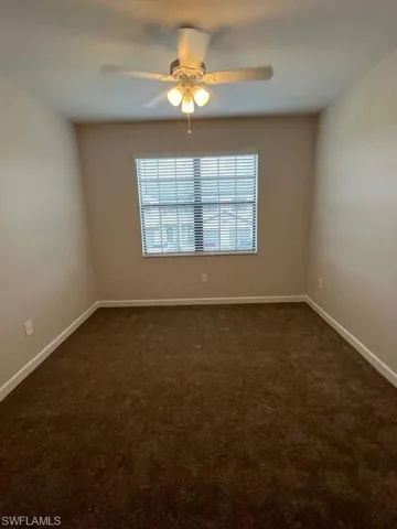 Empty room with dark carpet and ceiling fan