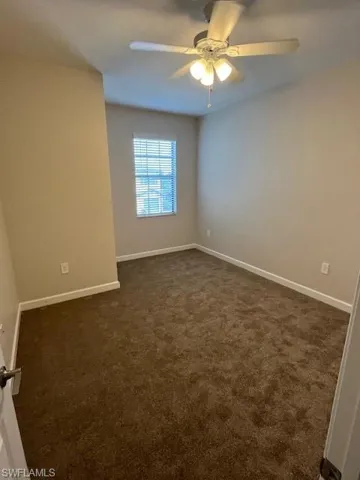 Empty room with dark colored carpet and ceiling fan