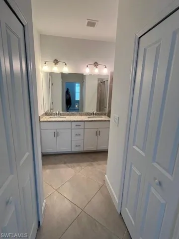 Bathroom with double vanity, light tile patterned floors, and a shower