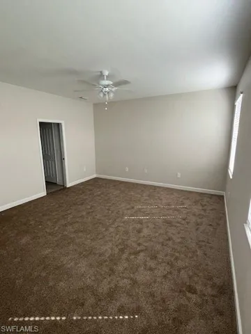 Unfurnished room with dark colored carpet and ceiling fan