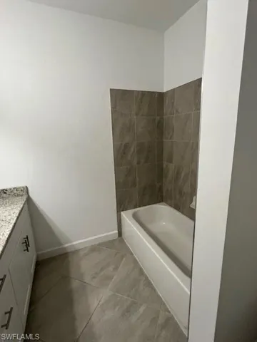 Bathroom featuring a garden tub, vanity, and light tile patterned flooring