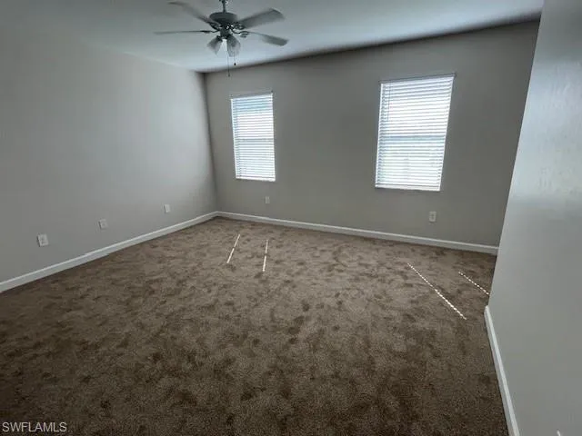 Carpeted spare room with healthy amount of natural light and a ceiling fan
