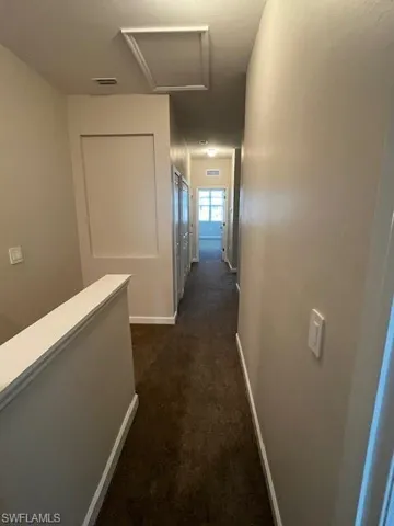 Hallway featuring dark carpet and attic access