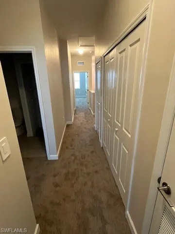 Hall with dark colored carpet and baseboards