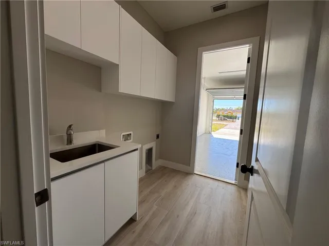 Laundry area with cabinet space, a sink, hookup for a washing machine, and hookup for an electric dryer