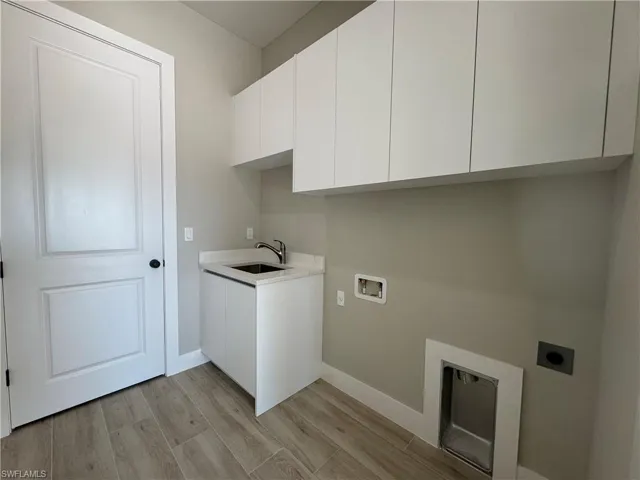 Laundry area with cabinet space, a sink, hookup for a washing machine, and hookup for an electric dryer
