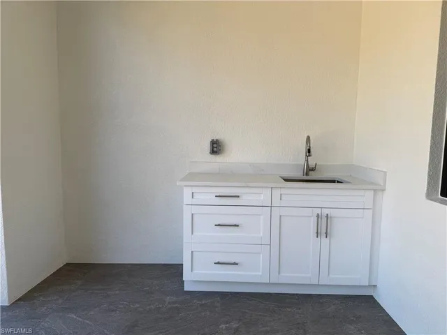 Bar featuring white cabinets, a textured wall, and light counter top