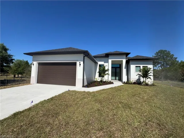 Prairie-style home with stucco siding, concrete driveway, an attached garage, and roof with shingles