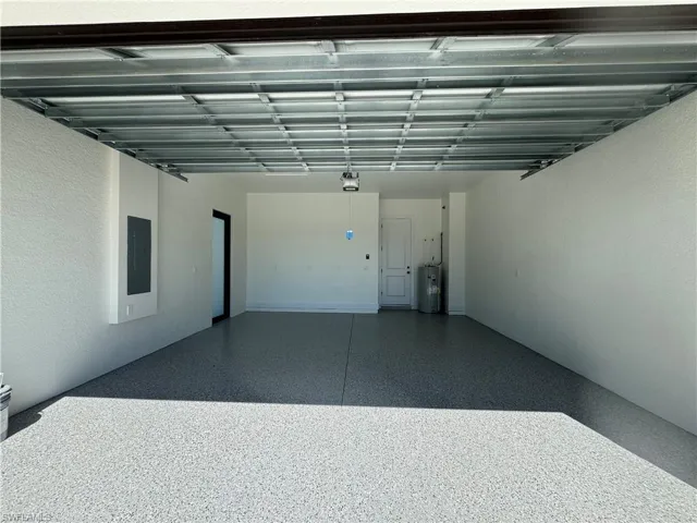 Garage featuring electric panel, a textured wall, and electric water heater