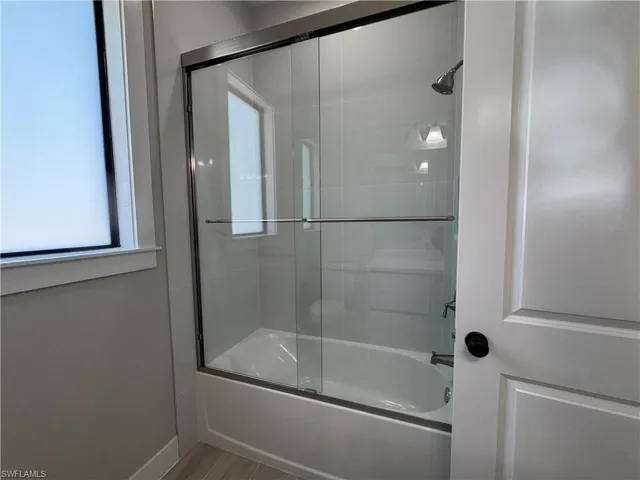 Full bathroom with healthy amount of natural light, bath / shower combo with glass door