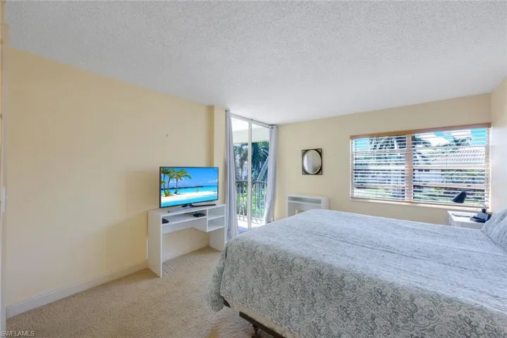 Bedroom featuring access to exterior, a textured ceiling, and light carpet