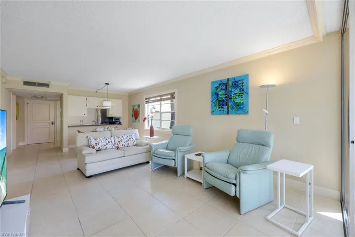 Living area featuring crown molding, light tile patterned floors, and a textured ceiling