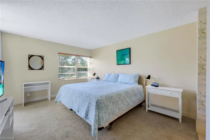 Bedroom with a textured ceiling and light carpet
