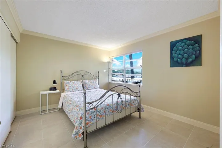 Bedroom featuring ornamental molding, a textured ceiling, a closet, and light tile patterned flooring