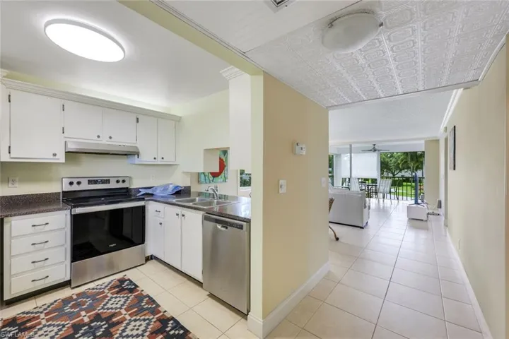Kitchen featuring stainless steel appliances, white cabinets, light tile patterned flooring, and open floor plan