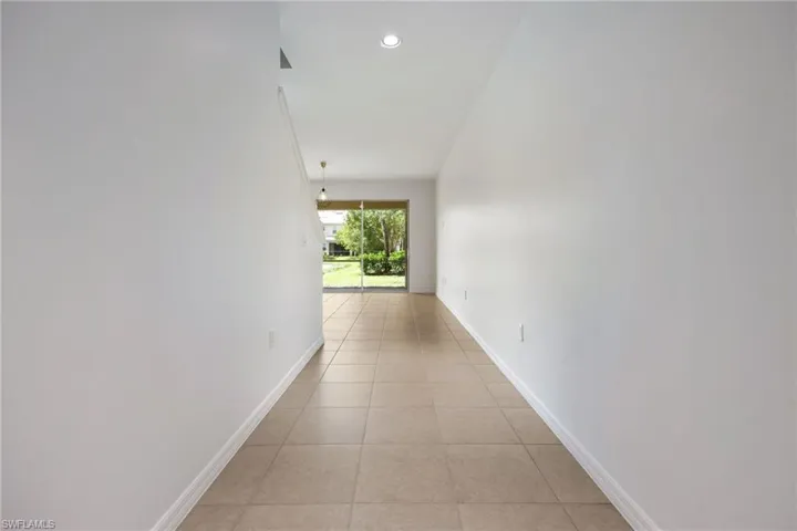 Corridor with light tile patterned flooring and recessed lighting
