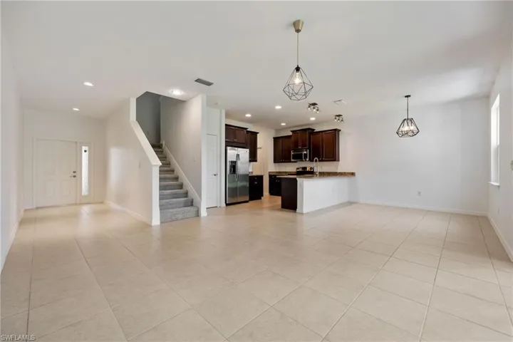 Unfurnished living room featuring light tile patterned flooring, stairs, recessed lighting, and a chandelier