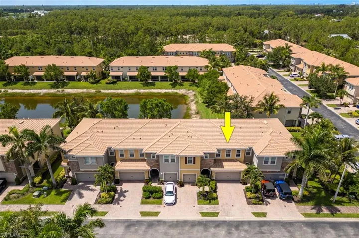 Aerial view of residential area with a heavily wooded area and a large body of water