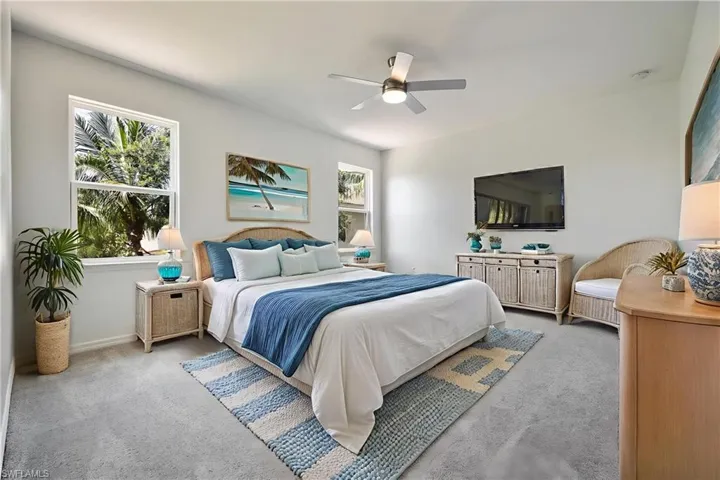 Carpeted bedroom with ceiling fan and baseboards