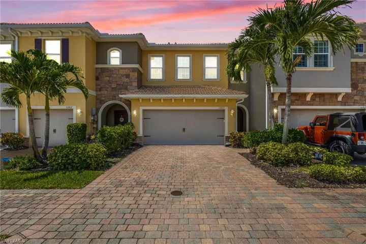 View of front of property with stucco siding, stone siding, a garage, decorative driveway, and a tiled roof
