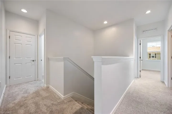 Corridor with an upstairs landing, light carpet, and recessed lighting