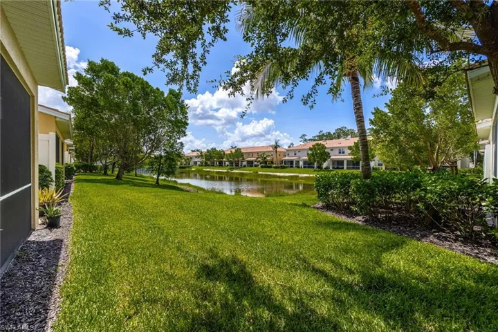 Back View of grassy yard featuring a water view and a residential view