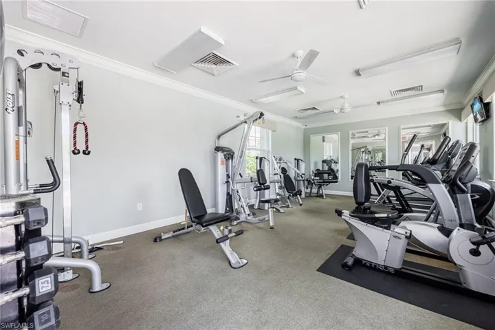 Gym with a ceiling fan and ornamental molding