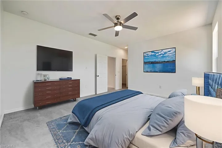 Carpeted bedroom with ceiling fan and baseboards