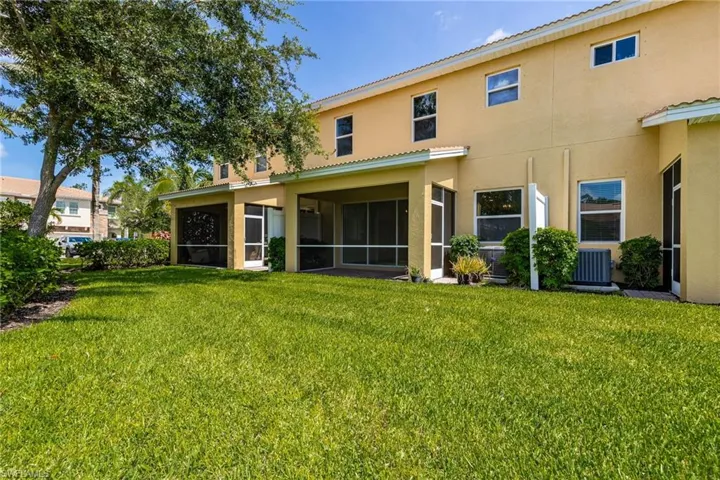 Back of house featuring stucco siding, a lawn, and a sunroom
