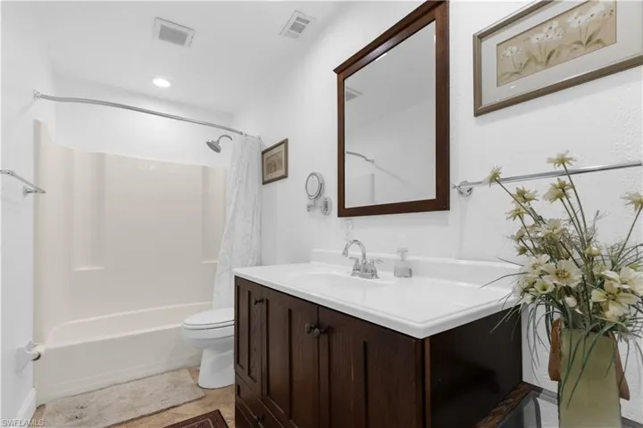 Bathroom featuring vanity and shower / bath combination with curtain