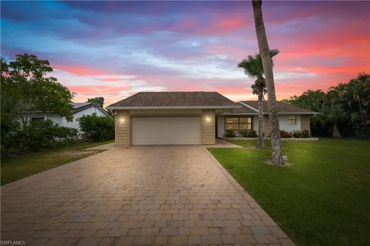 View of front of home with decorative driveway, a garage, and a front yard