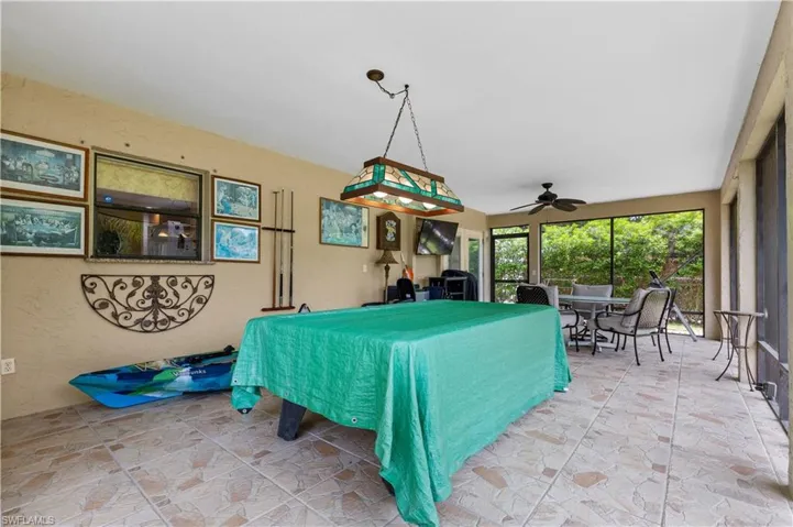 Rec room with billiards table, ceiling fan, vaulted ceiling, and light stone finish floors