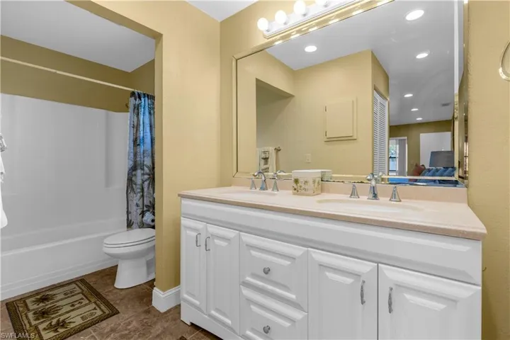 Bathroom featuring double vanity, shower / bath combo, and tile patterned floors