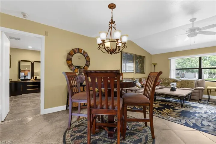 Dining space featuring vaulted ceiling, a chandelier, a ceiling fan, and light tile patterned floors