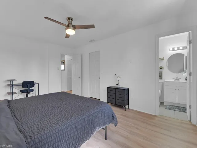 Bedroom featuring light hardwood / wood-style flooring, ensuite bath, ceiling fan, and sink