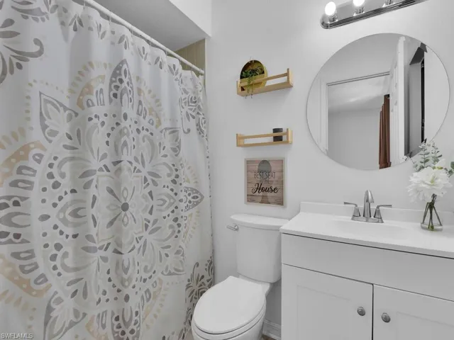 Bathroom with a shower with shower curtain, vanity, and toilet