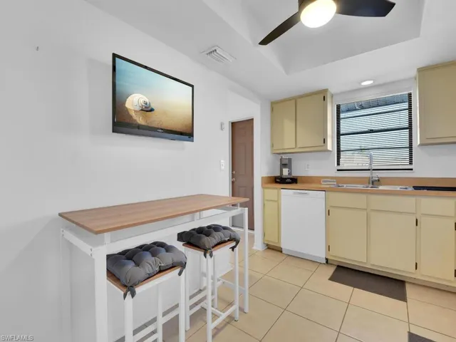 Kitchen with dishwasher, light tile patterned floors, cream cabinetry, and sink