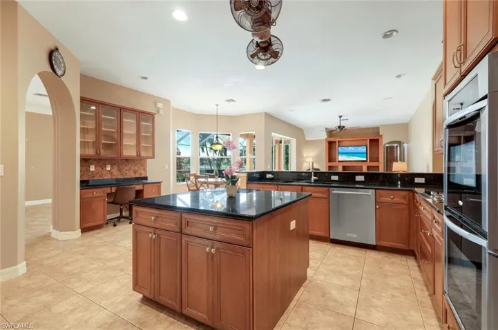 Kitchen also features desk area and additional cabinets with glass doors.