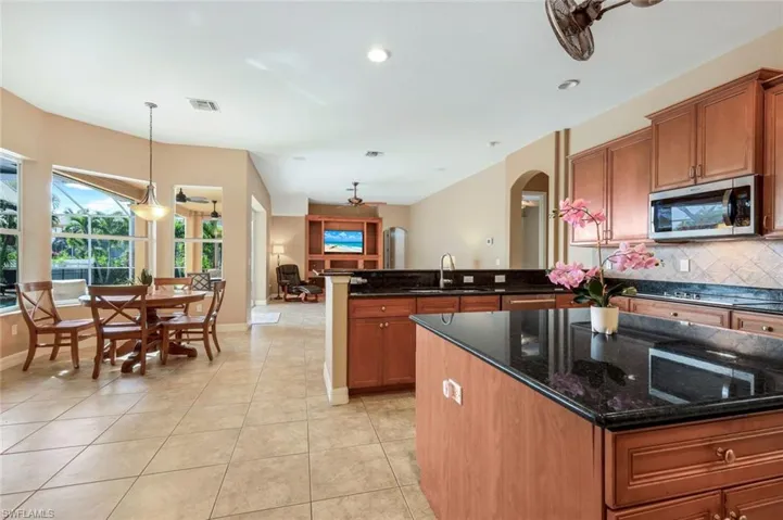 Kitchen featuring appliances with stainless steel finishes, tasteful backsplash, dark stone counters, light tile patterned floors, and decorative light fixtures