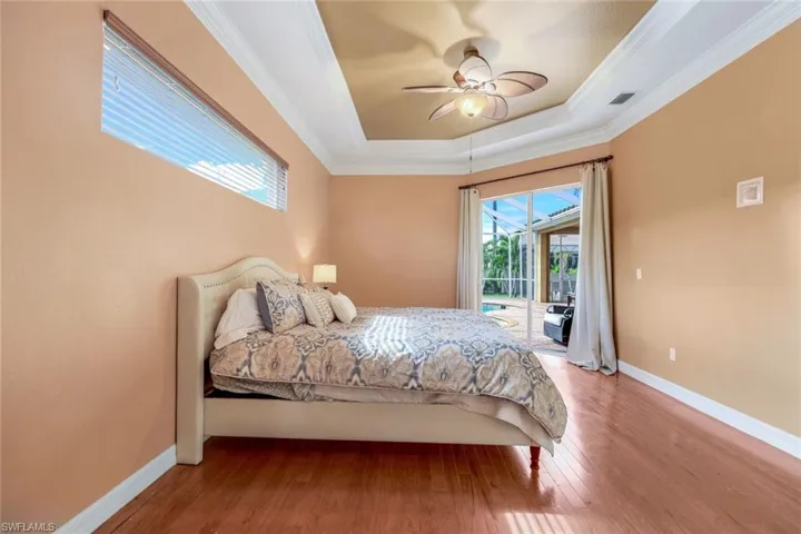Primary bedroom is spacious with tray ceiling, crown molding and access to the lanai/pool area.