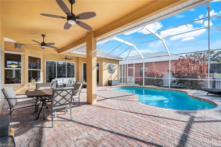 View of swimming pool and lanai with nice paver decking and ceiling fans.